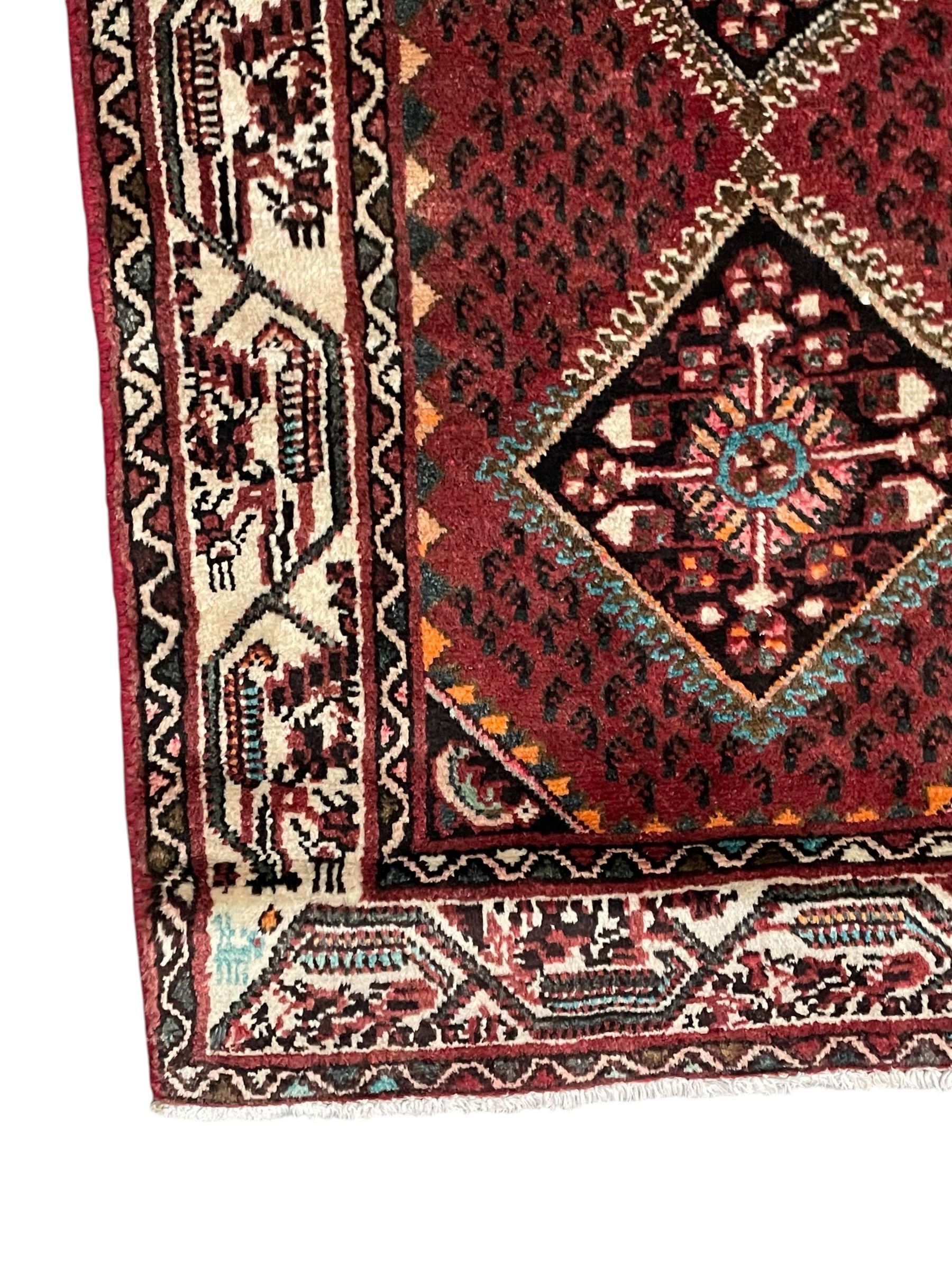 Persian Baluch red ground runner, seven lozenge medallions each decorated with stylised floral motifs, ivory border decorated with trailing pattern and Boteh motifs, within geometric guard stripes 