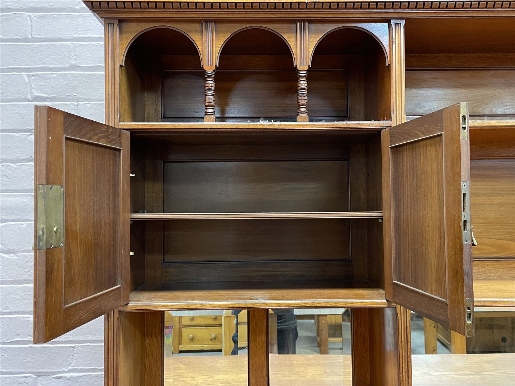 Late Victorian walnut dresser, the raised panelled back fitted with panelled cupboards, shelves and bevelled mirrors, moulded rectangular top over three drawers and cupboards, the left-hand cupboard fitted with two slides and the right-hand cupboard fitted with revolving drinks stand, on turned feet
