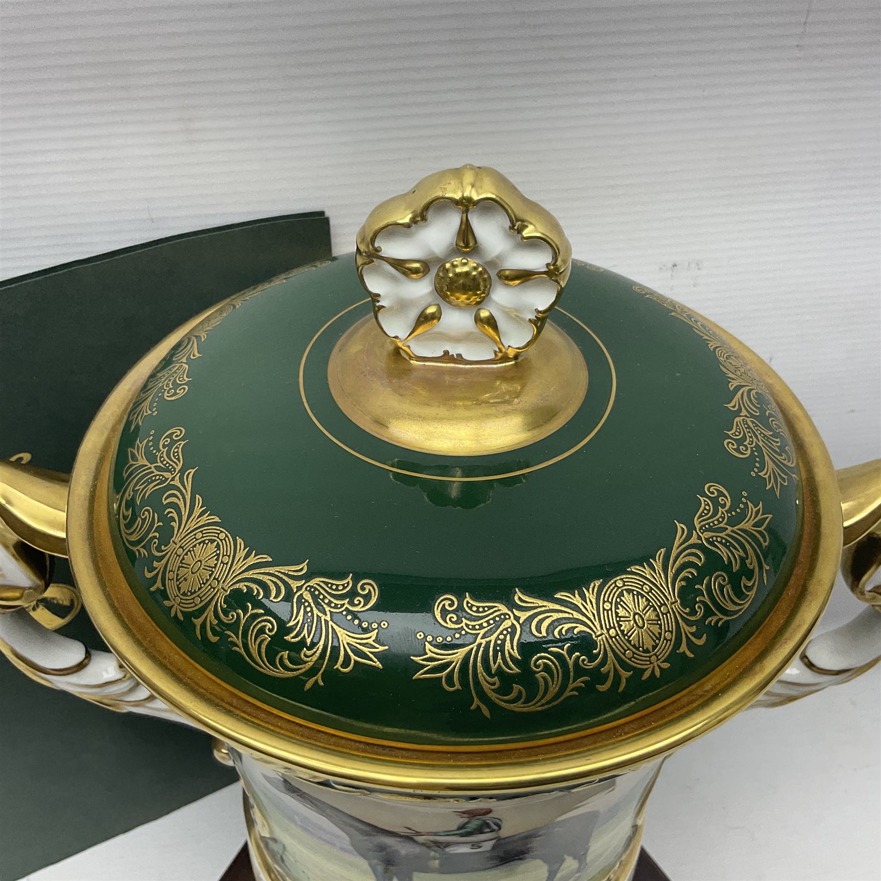 Aynsley twin handled racing cup and cover, to commemorate 'The Golden Jubilee of the Revival of The Yorkshire Cup', the handles inscribed '1927' and '1977', the green body painted by E. Woodhouse with Joe Childs up on Trimdon, the reverse with the winners, the domed cover with a Yorkshire rose finial, limited edition no. 4 of 50, on hexagonal wooden base with certificate, H34cm