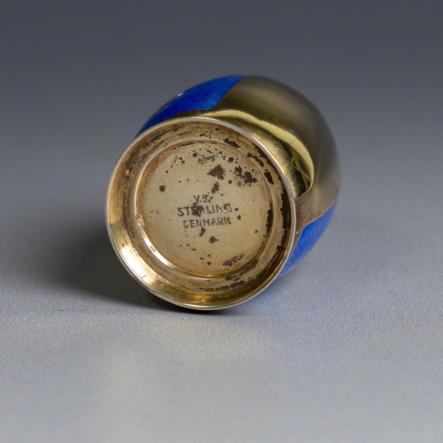 Mid 20th century Danish silver-gilt and guilloche enamel cruet set by Volmer Bahner, comprising pepper shaker, open salt and salt spoon, the spoon handle and bowl interior with blue basse taille enamel and vine motif, the pepperette with panels of blue guilloche enamel with similar applied vine decoration, all stamped Sterling Denmark VB, pepperette H4cm