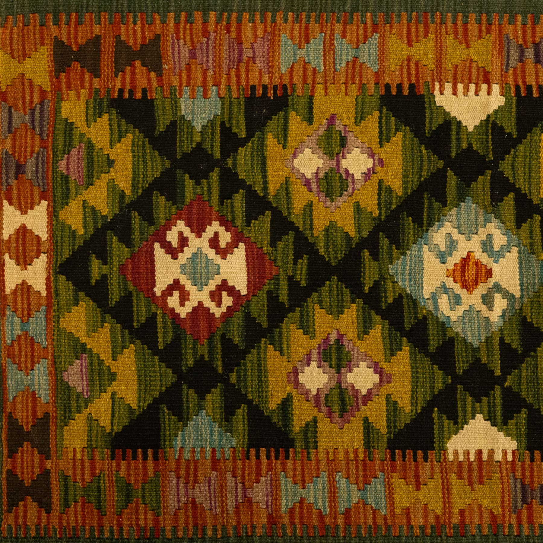 Chobi flatweave kilim runner with a repeating stepped diamond medallion design in live green, rust, teal, purple, and ivory, framed by chevron and geometric borders
