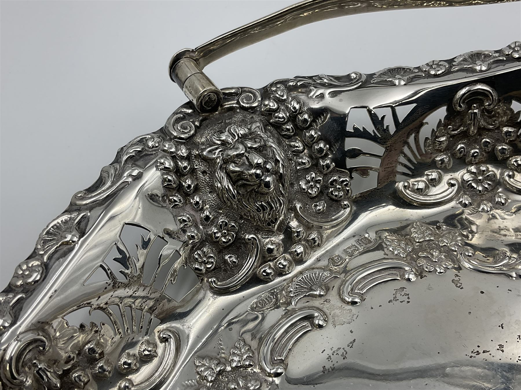 Edwardian silver swing handled basket, of navette form, with four repousse lion masks to each corner and with pierced and embossed floral, scroll and shell decoration to sides, base and handle, hallmarked Charles Horner, Birmingham 1906, height including handle H20cm