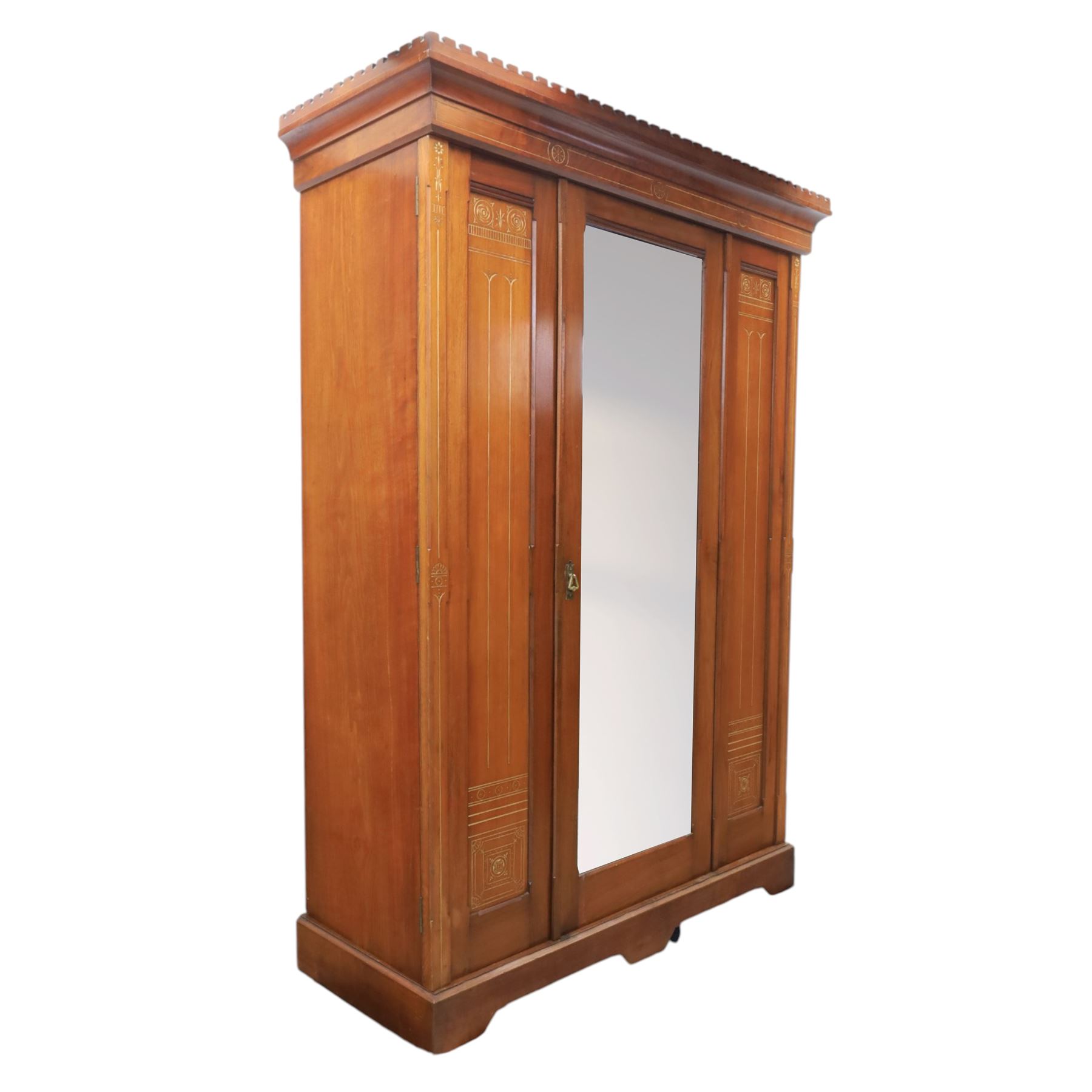 Aesthetic Movement walnut parcel gilt wardrobe, the crenellated top, above central mirrored door opening to reveal hanging space, four opened and two closed draws