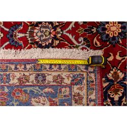 Central Persian Markazi Mahal hand-knotted carpet, terracotta red field, with an all-over scrolling vine design issuing with palmettes, rosettes, and serrated leaves, linked by ivory vinery, deep cobalt blue main border with floral ornamentation, flanked  by multiple guard stripes of repeating geometric motifs, with cotton fringe ends