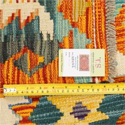 Afghan Chobi kilim flatweave runner with a repeating stepped diamond medallion design in live green, rust, teal, purple, and ivory, framed by chevron and geometric borders