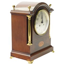 Edwardian-French mahogany cased mantle clock c1910 in a break-arch case with brass finials and recessed brass columns, with inlaid satinwood stringing and conche inlay to the front, raised on a short plinth with bracket feet, twin train movement with rack striking, sounding the hours and half-hours on a coiled gong.
With pendulum and key.