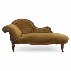 Victorian walnut framed Chaise longue, with carved scroll decoration and an out-swept buttoned upholstered, padded back and scroll end, seat upholstered mustard coloured velvet fabric, raised on turned legs with ceramic castors 