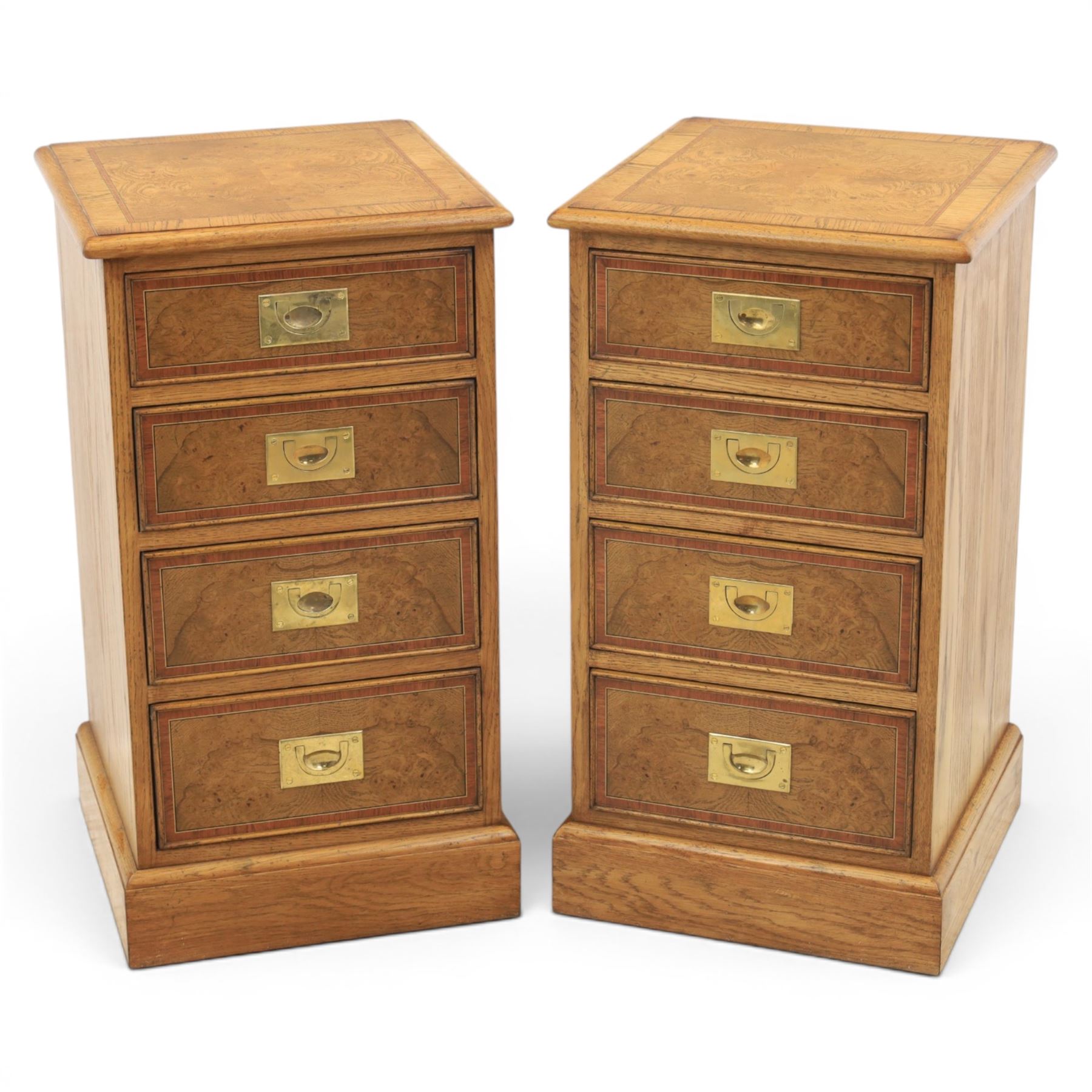 Pair of burr oak bedside tables with campaign brass handles, inlaid and crossbanded top, above four graduating drawers with cockbeaded edges, raised on a plinth base 