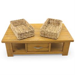 Contemporary pine coffee table, rectangular planked top with moulded edge, fitted with a central drawer to either side with brushed metal handle, flanked by two open compartments housing wicker basket drawers, plain sides, raised on square block feet