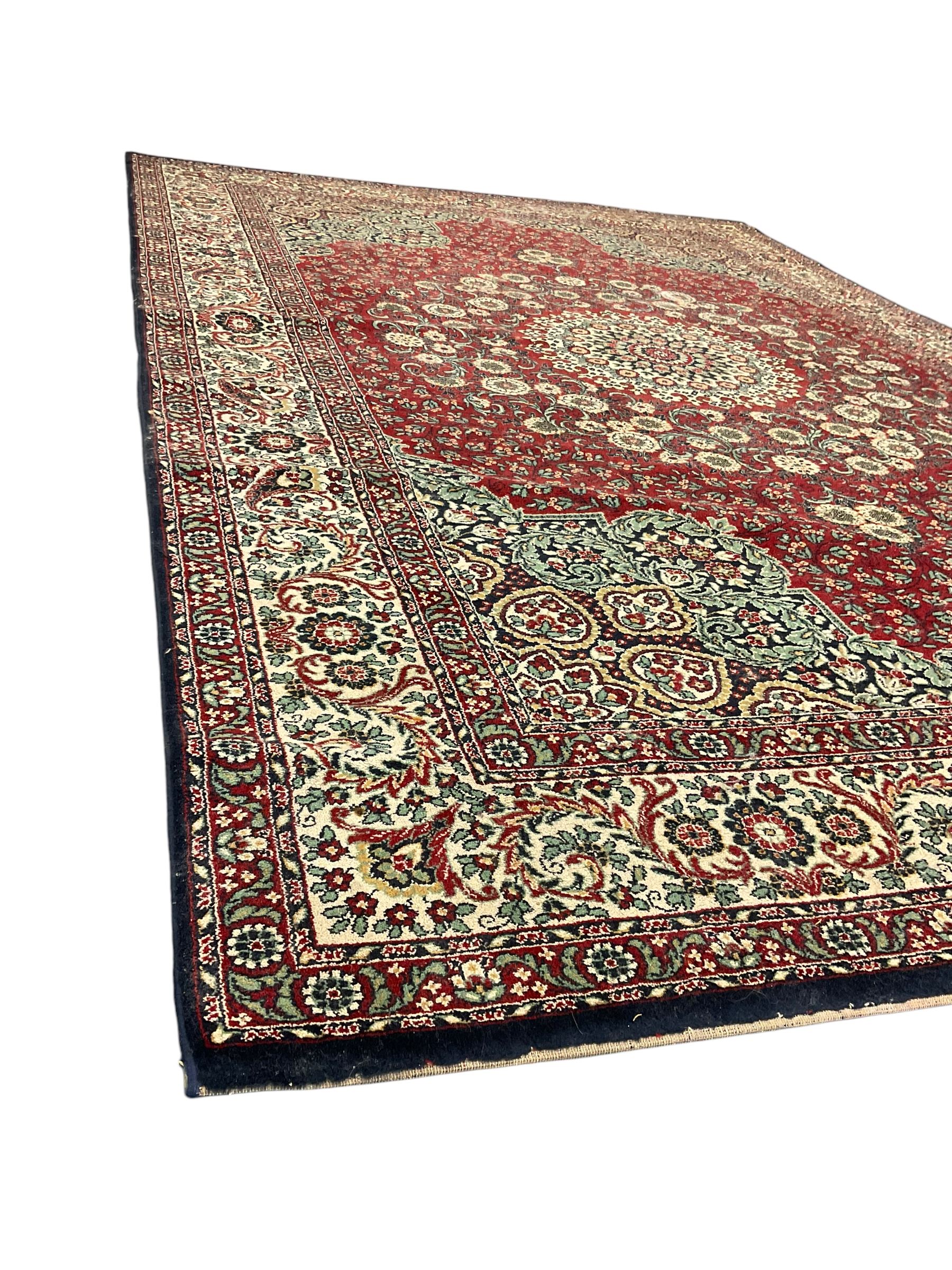Persian design crimson ground carpet, the central rosette medallion surrounded by scrolling leaves and flower heads, the spandrels decorated with floral design and scrolling foliage, repeating border within guard stripes