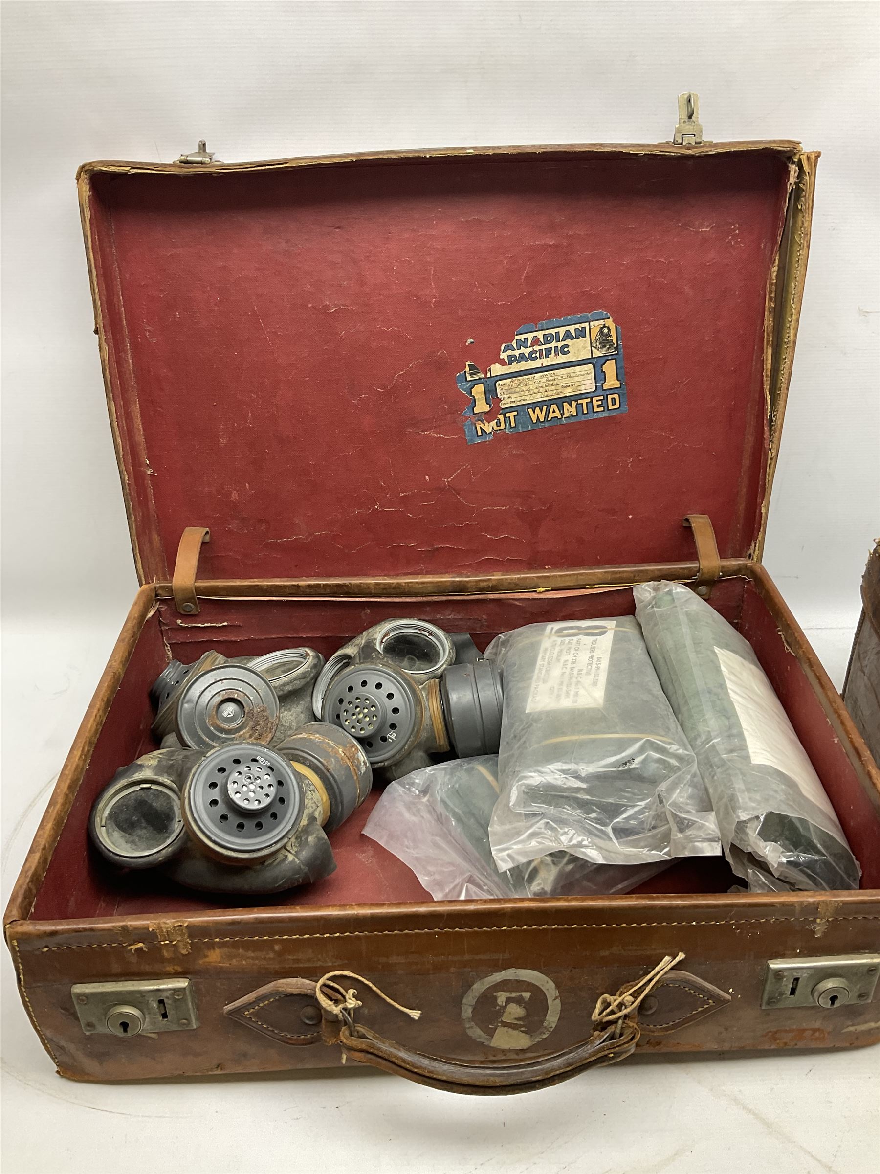 Early 20th century leather suitcase marked to the top 'Major P.M. Newton R.E. Crossways, Bridlington, East Yorkshire' 60 x 40cm; another similar leather suitcase marked W.D. to the lid; three post-WW2 respirators; and three unopened pairs of British Army N.B.C. (Nuclear Biological Chemical) No.1 Mk.III Trousers Protective (8)
