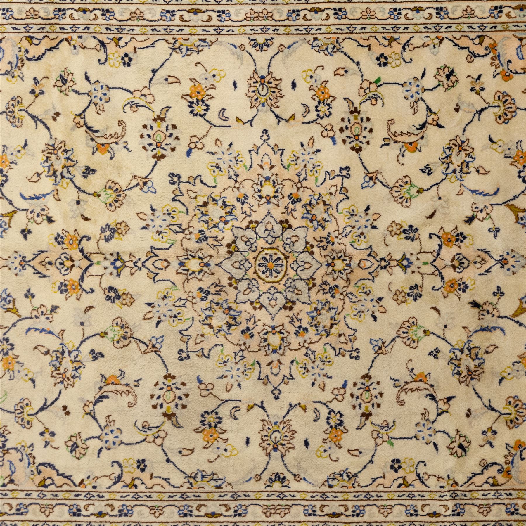 Central Persian Kashan hand-knotted carpet, ivory ground with central rosette medallion surrounded by scrolling floral vines and palmettes, field framed by a meander border flanked by multiple guard stripes, with cotton fringe end and a replaced fringe end