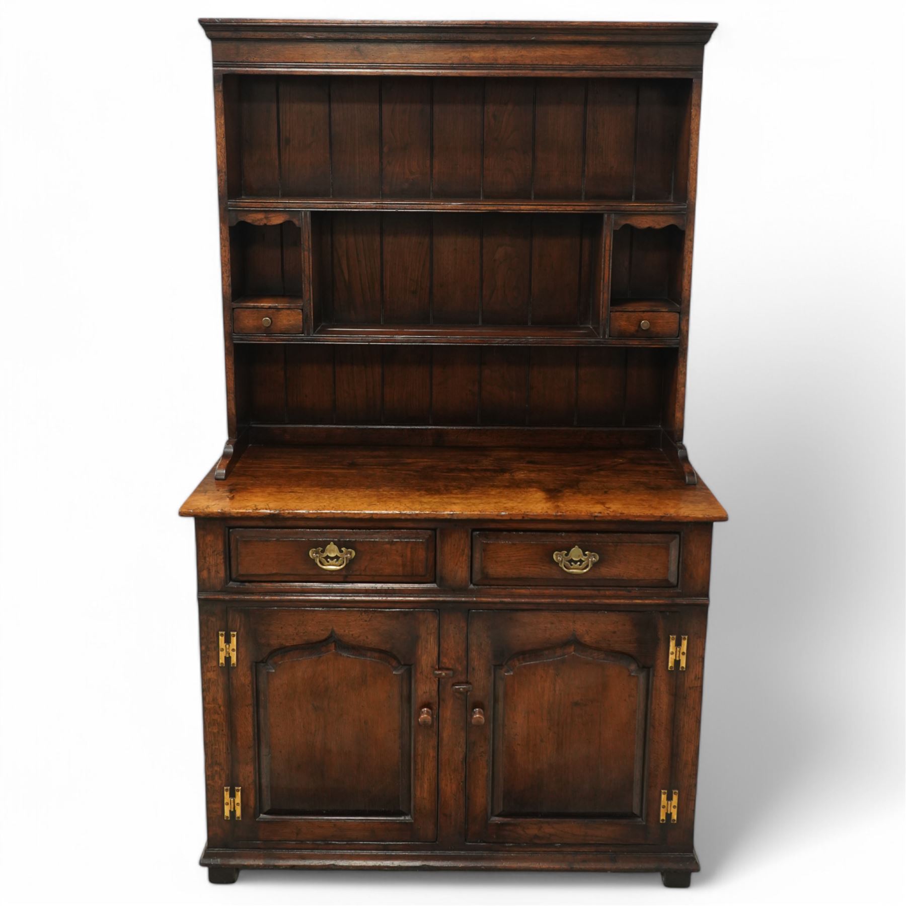 Contemporary georgian style oak dresser, open rack top with two shaped shelves and small side drawers, base with rectangular top over two drawers with brass swing handles, twin arched panelled doors below, on bracket feet