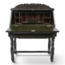 Early 20th century Chinese export carved hardwood writing bureau, the sloped fall front deeply carved with a narrative figural scene beneath pine and prunus trees, above a pair of rectangular carved panels, the shaped crest rail with entwined dragons, interior fitted with pigeonholes and a central drawer, on figural front supports with shaped stretcher