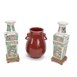 20th century Chinese sang de boeuf vase of baluster form with elephant head handles, togehter with a pair of famille rose vases decorated with floral decoration and insects, upon wooden stands   