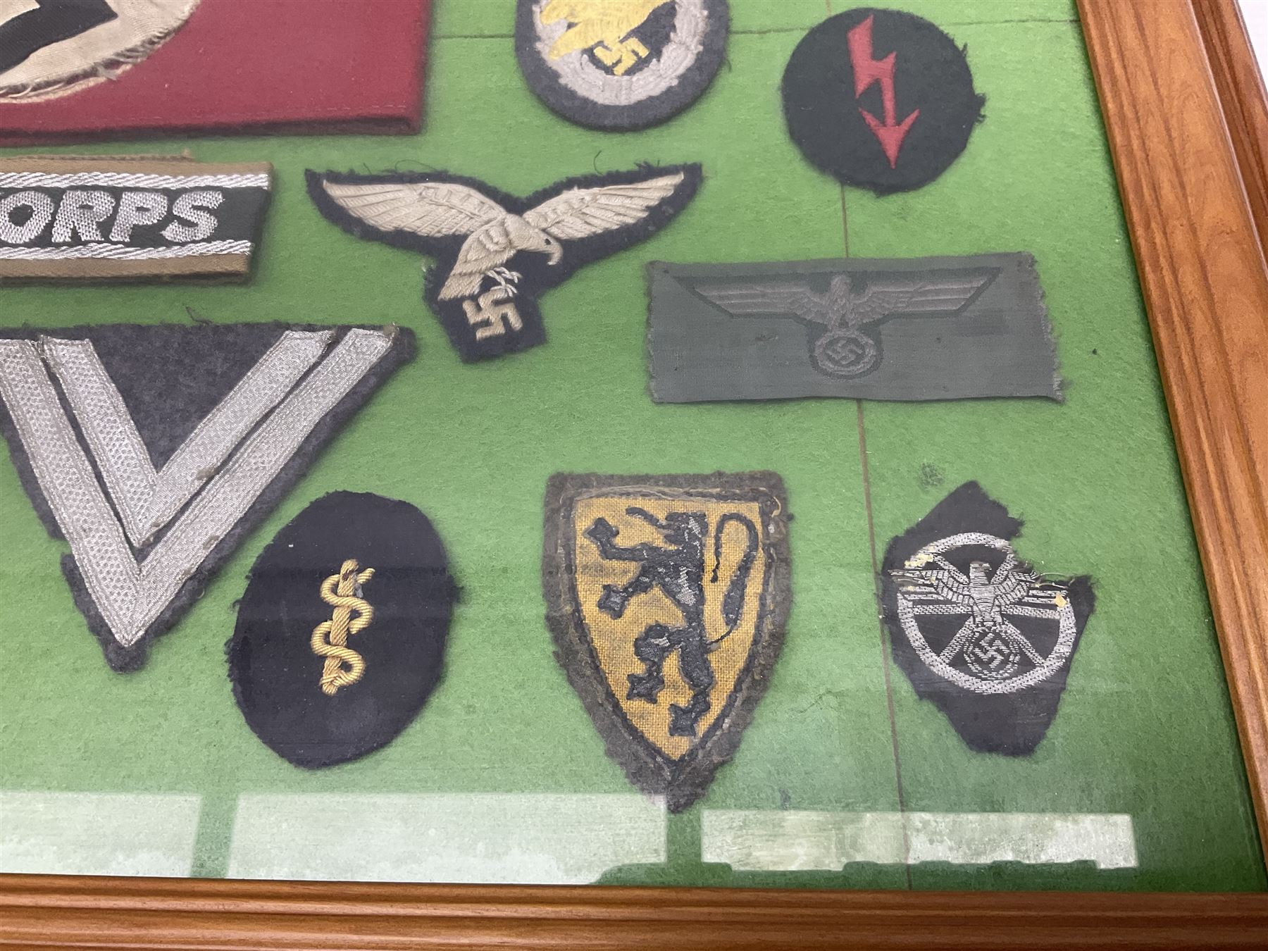 Framed display of thirty-four WWII German cloth badges including Luftwaffe pilot, Paratrooper, Afrikakorps cuff title, sleeve insignia for 'SS' Foreign Volunteers, various breast eagles including Luftwaffe, Army etc, RAD badges, Party Armband, rank and trade insignia, cap insignia etc; 40 x 50cm in modern pine frame
