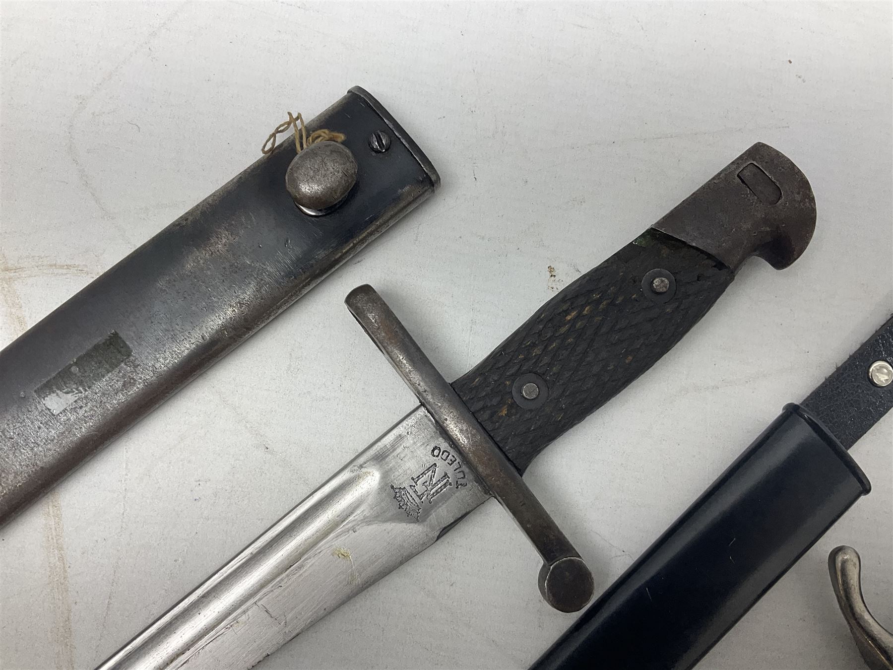 Spanish Model 1941 Bolo bayonet the 24cm steel blade marked 'NF Toledo 4992 H'; in steel scabbard marked '5828 F' L39.5cm overall; Arabian Jambiya type knife with white metal covered grip and jewelled scabbard, inscribed script to blade; and replica WW2 German dagger/knife in scabbard (3)