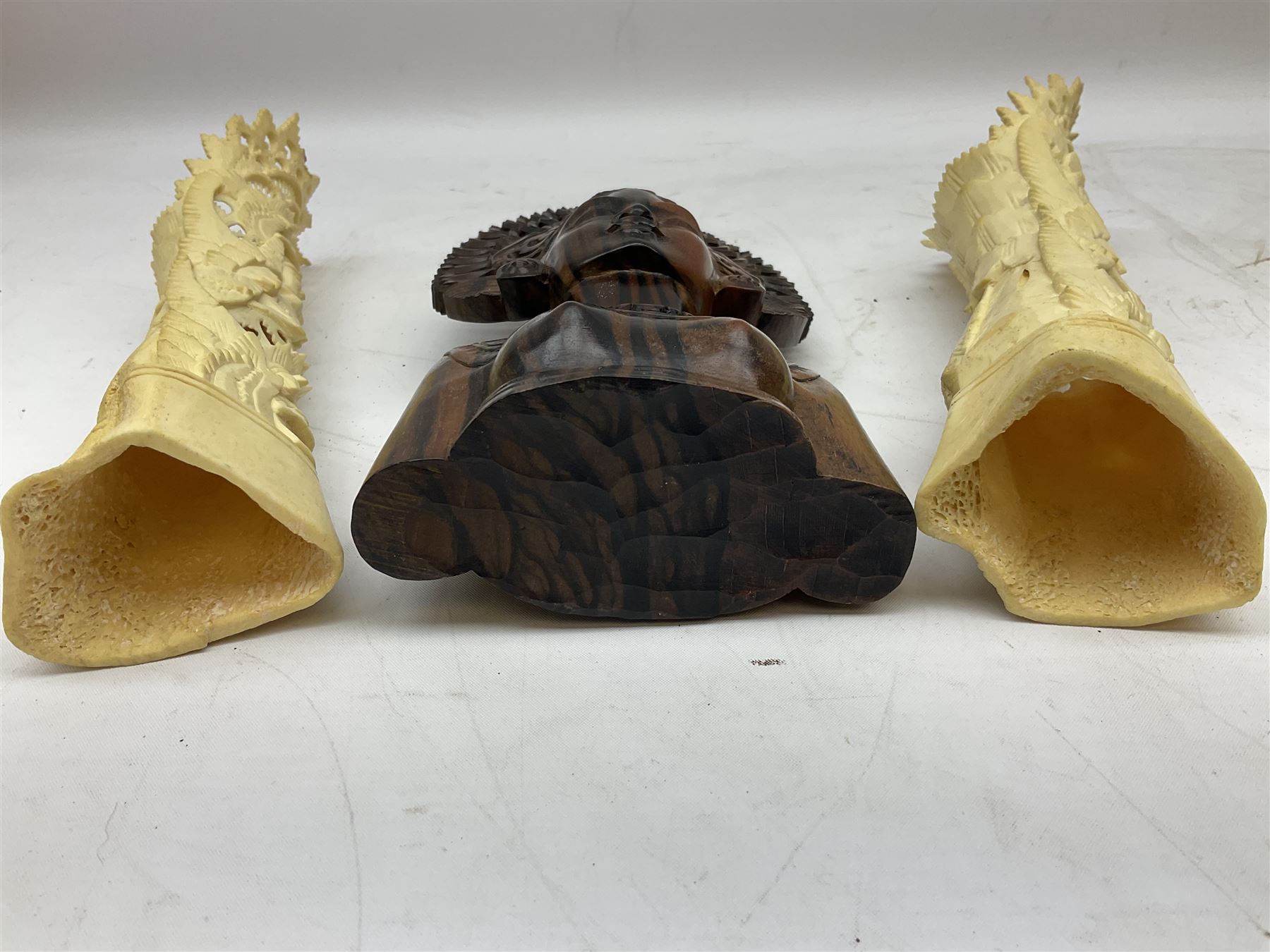 Hardwood bust of an Indoniesian Goddess, carved wearing a pierced headdress, from Klungkung, Bali, H20cm, together with a pair of bone carvings of deity figures, and a carved wood Netsuke in the form of a Chinese dragon