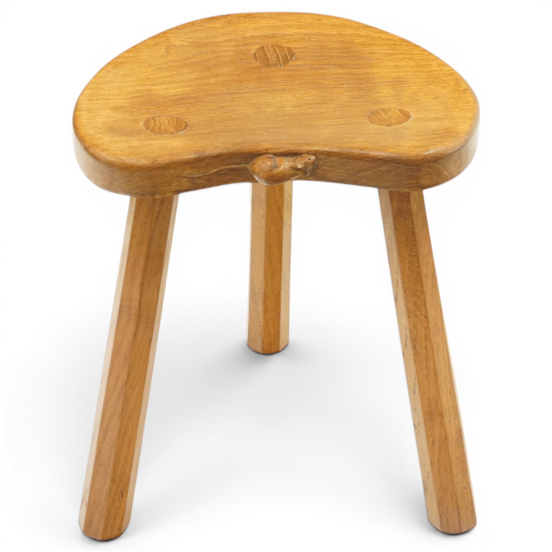 Mouseman - oak three-legged milking stool, dished kidney-shaped seat, raised on three octagonal splayed supports, with carved mouse signature, by the workshop of Robert Thompson of Kilburn