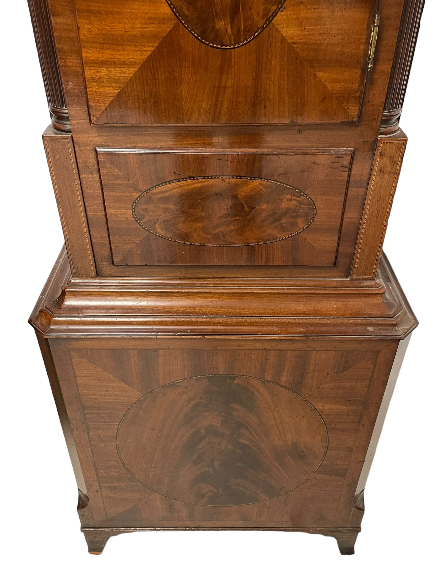 John Morgan of Aberystwyth - fine George IV mahogany 8-day longcase clock c1820, with a raised swan necked pediment, ball and eagle finial and deep inlaid frieze beneath, square hood door with a glazed circular wooden bezel and canted corners, long trunk with reeded quarter columns and a wavy topped door, rectangular plinth on bracket feet, circular painted dial with Roman numerals, minute track, makers name, and brass stamped hands, rack striking four pillar movement with a recoil anchor escapement, striking the hours on a bell. With weights and pendulum. 
John Morgan is recorded as working in Aberystwyth 1816-35. 