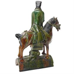 Chinese Ming dynasty Sancai Glazed Roof Tile, modelled as a dignitary on horseback, dressed in a long robe with voluminous folds, wearing an official's cap, upon a half cylinder tile, H40cm