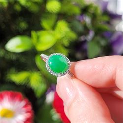 Platinum jadeite and diamond cluster ring, single oval cabochon cut jadeite of 2.20 carat, surrounded by round brilliant cut diamonds and diamond set shoulders, stamped Plat