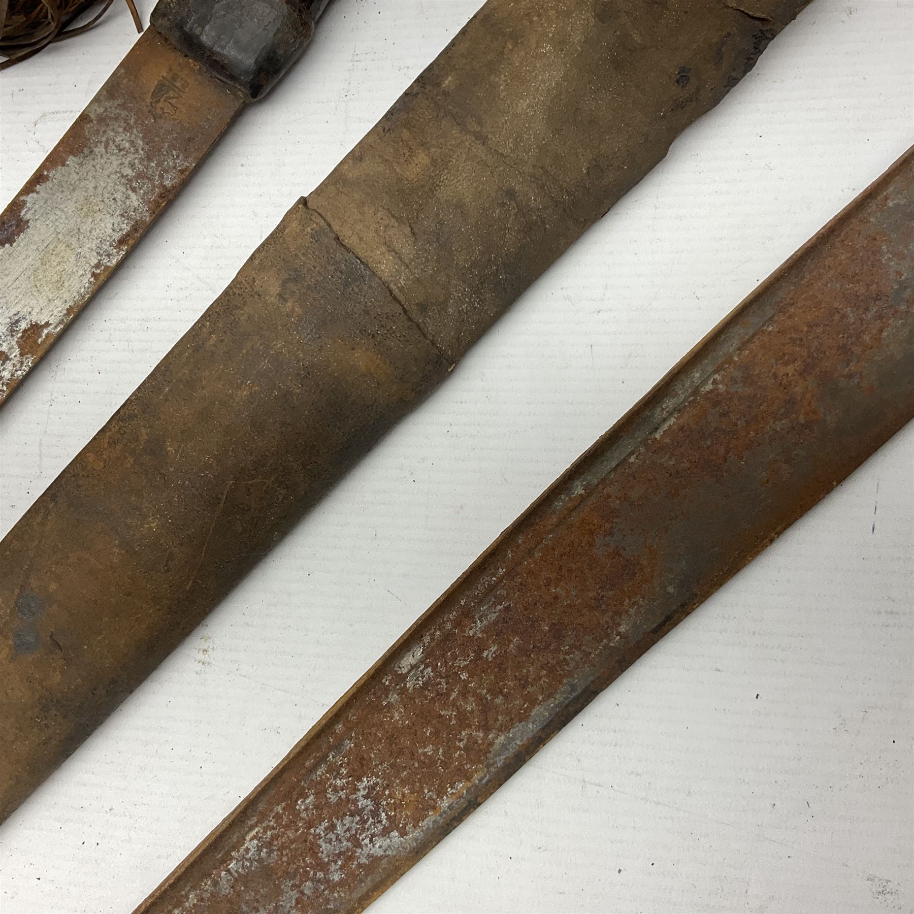 Mandingo sword, the 63cm plain curving steel blade marked with a horses head and the initials G.S.; leather covered grip with metal ribbed spherical pommel; in decorative leather leaf scabbard mounted with tassels and roundels L84cm overall; and a North African flyssa sword in poor condition with wooden scabbard (2)