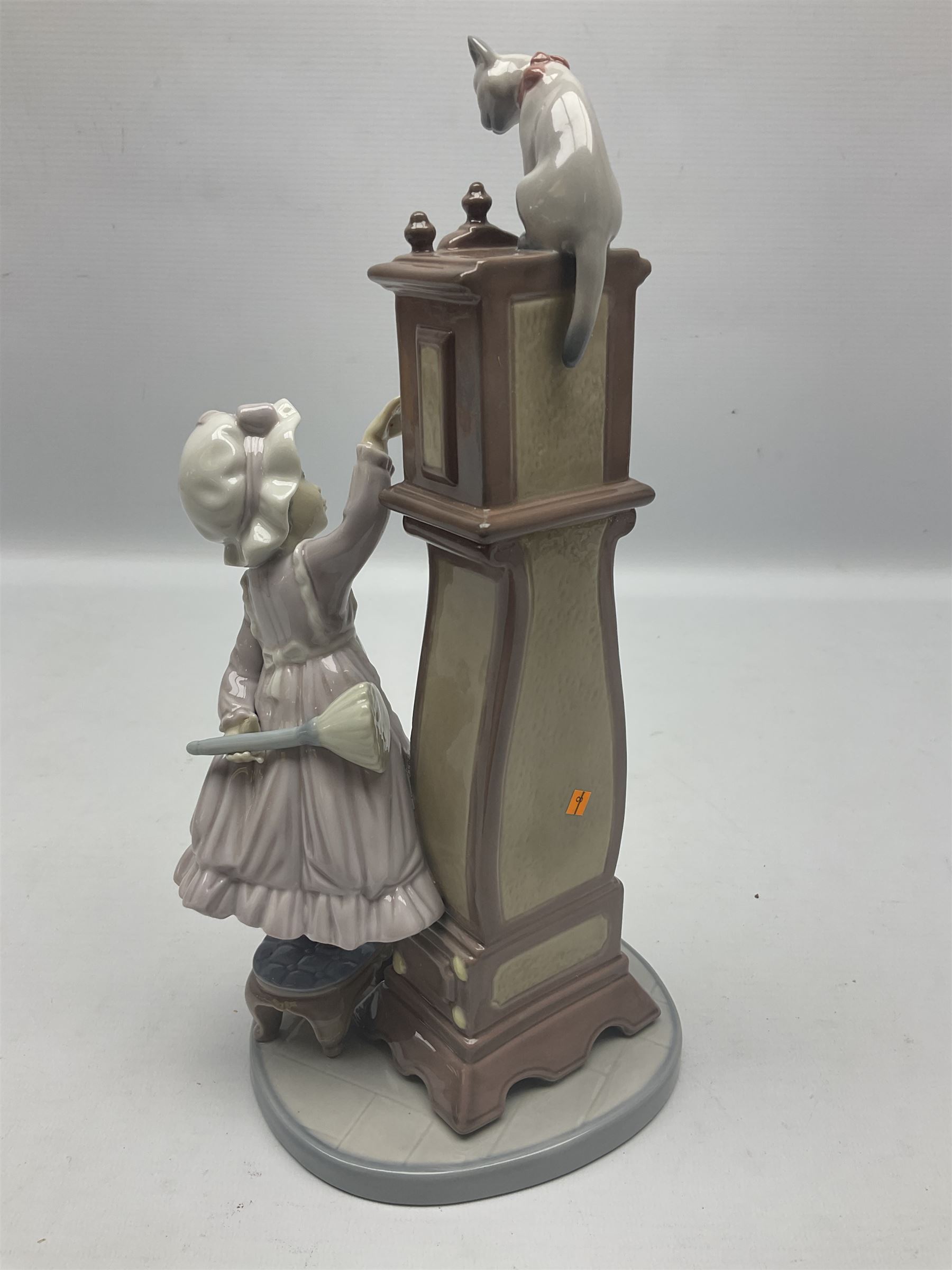 Lladro figure, Bedtime, modelled as a young girl reaching for her pet cat upon grandfather clock, sculpted by Vincente Martinez, with original box, no 5347, year issued 1986, year retired 1998, H28cm