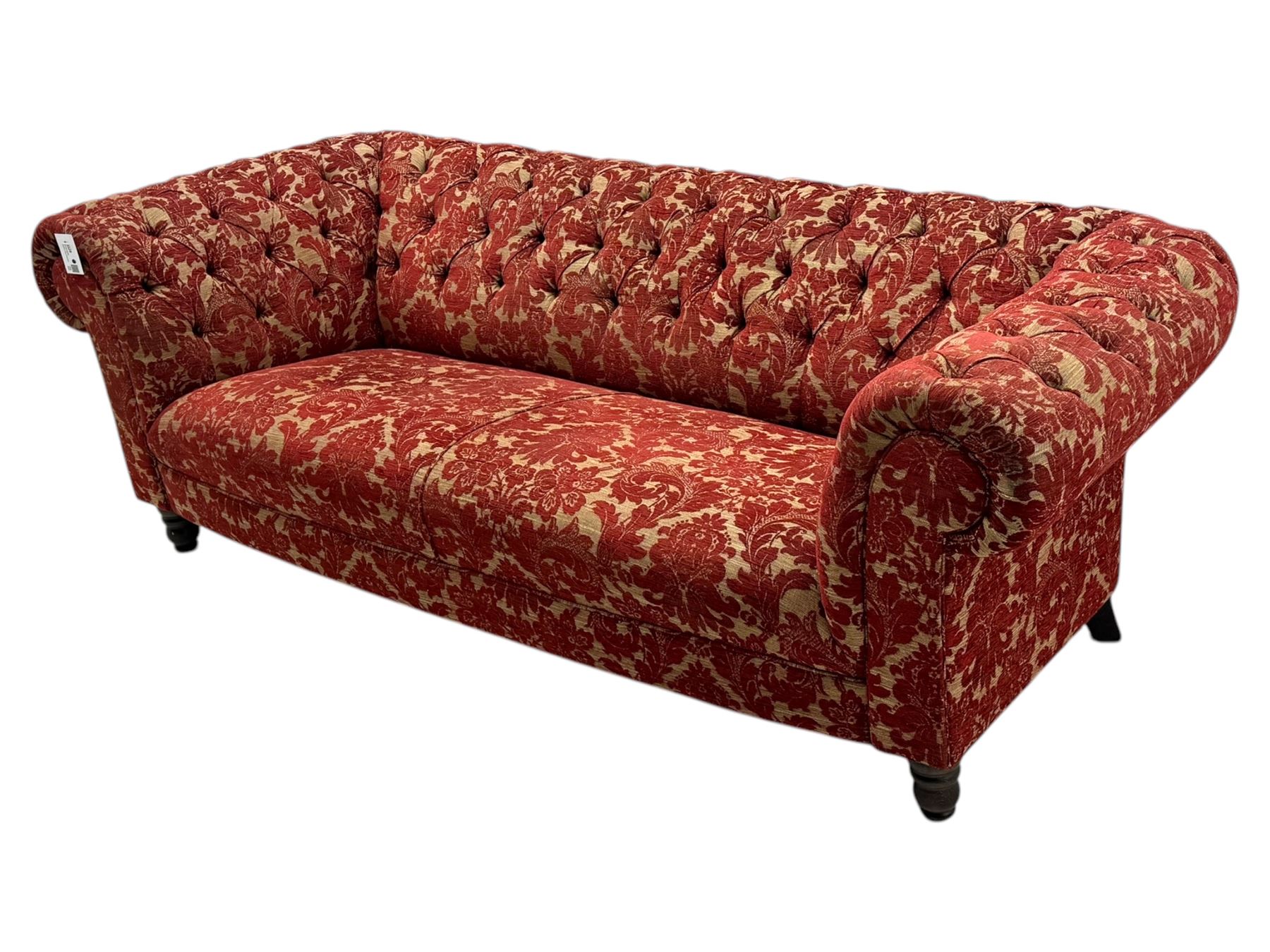 Late 20th century upholstered Chesterfield sofa, in red damask floral fabric, with deep buttoned back and arms, scrolled arms at equal height to back, on turned front supports