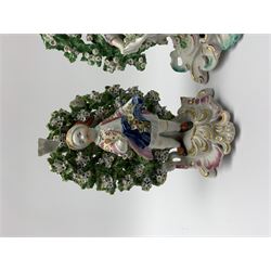 Near pair of bocage figures, the first an 18th century Derby example modelled as a young boy holding flowers, upon a gilt detailed scrolling base, with patch marks beneath, H17cm, together with a later example in the Chelsea-Derby style modelled as a young girl holding flowers, upon similar base, H18cm