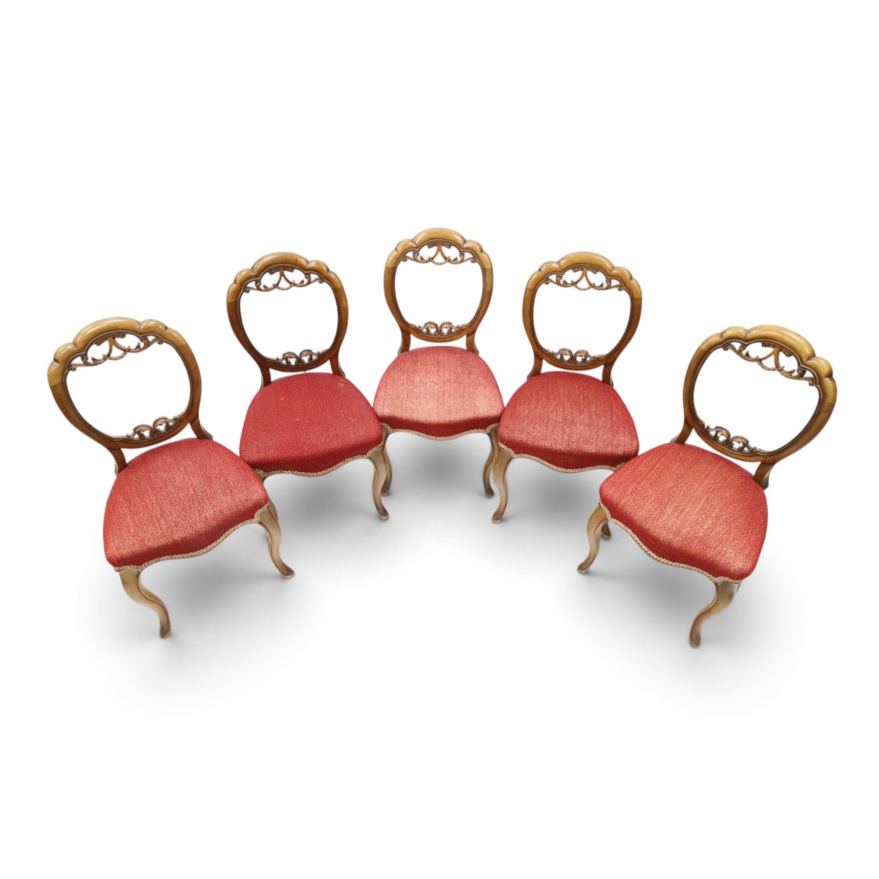 Set of five Victorian mahogany dining chairs, the scalloped balloon back with pierced scrolling acanthus leaf decoration, sprung seats upholstered in crimson fabric, on cabriole supports