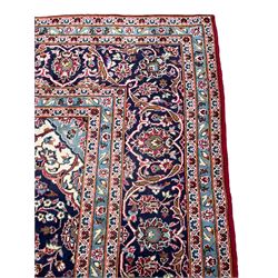 Central Persian Kashan crimson ground carpet, central  floral pole medallion with matching spandrels within a field of scrolling palmette motifs and foliage, the heavily banded indigo border with repeating plant motifs interlaced with scrolled branches