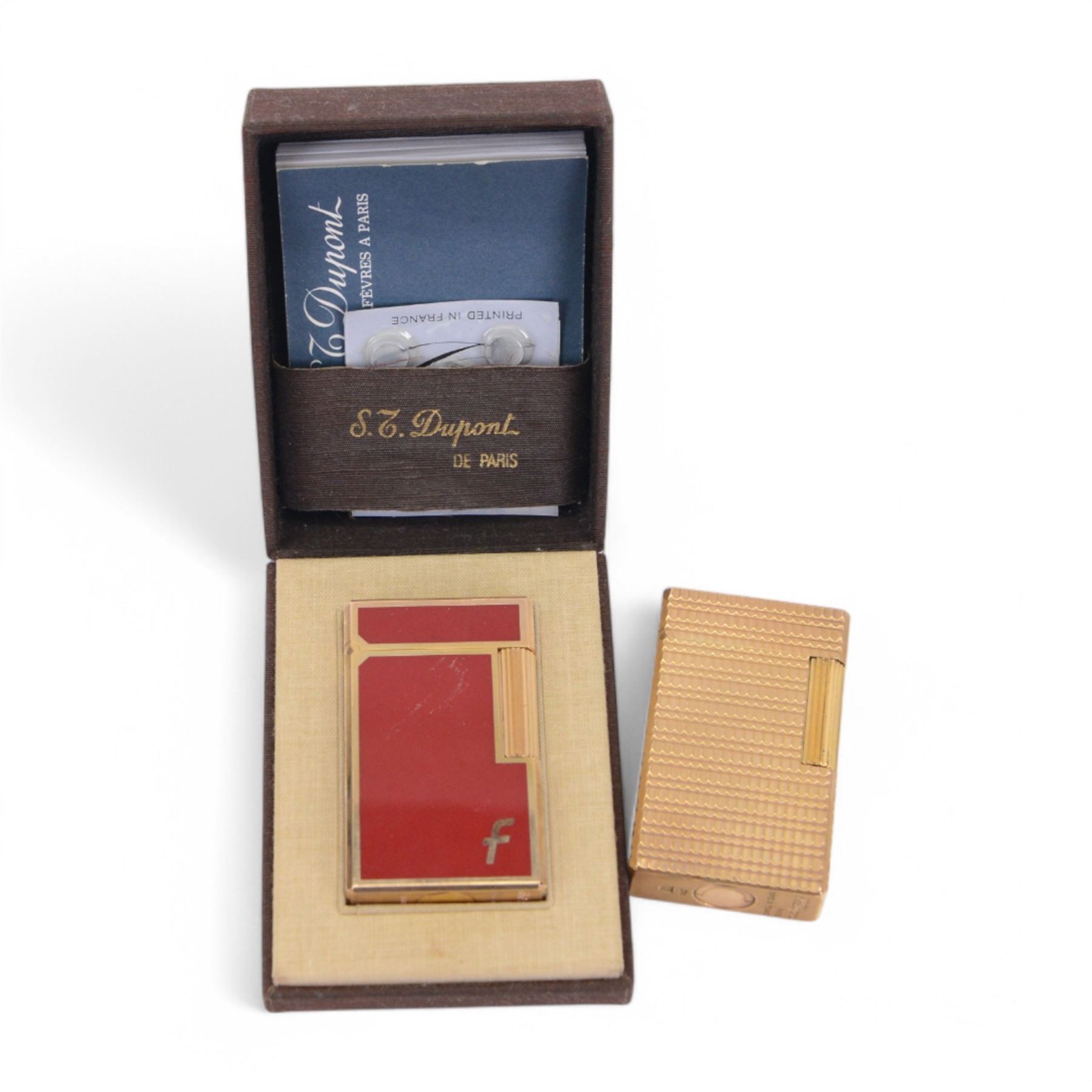 Two S.T. Dupont lighters, comprising red laque-de-chine example, boxed and a gold-plated textured example