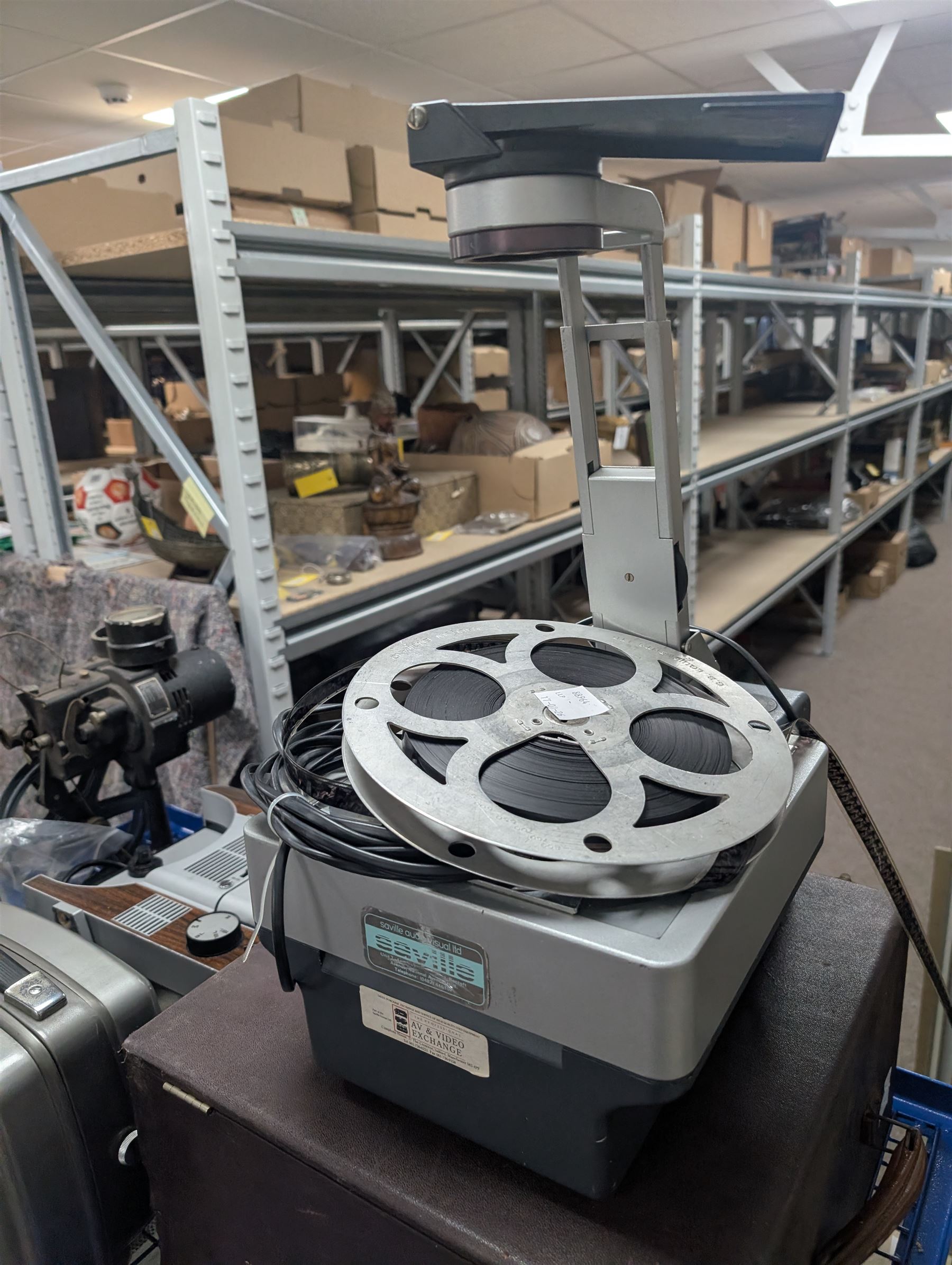 Collection of projectors, including Transpaque Junior overhead projector, Demo Comm 1 overhead projector, Bolex 18-9 Duo, Bolex 18-5, Pathescope Kid, Kodascope Model C, collection of video tapes and film reels, empty projector box, Kinay 816 editor, etc
