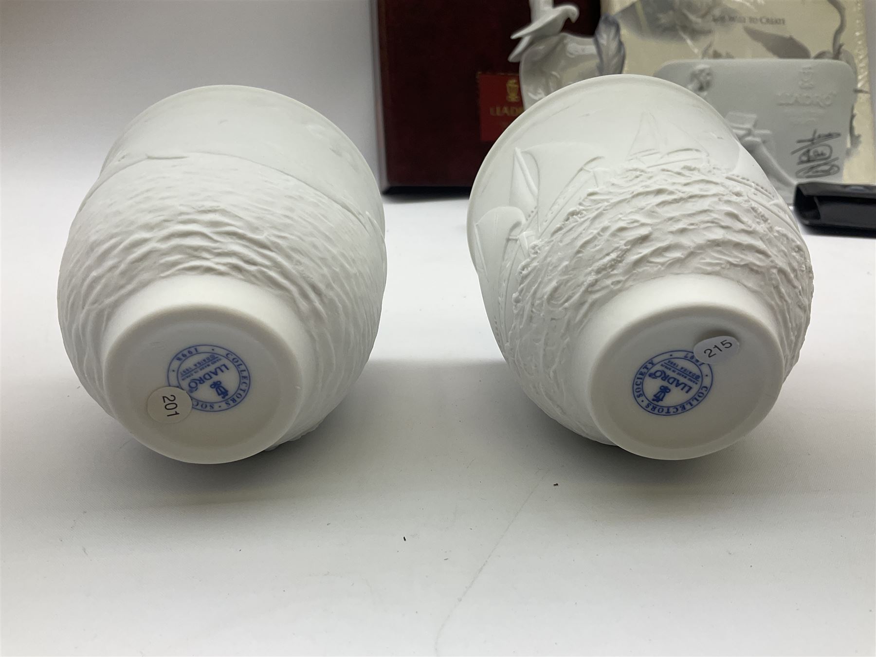 Lladro Collectors Society items, comprising of The Will to Create book, two candle holders; Sailing the Sea no 17665, Dolphins at Play no 17666, Plaque Bringing Us Together, key fob, leather wallet and a members joining pack with plaque, all in original boxes  