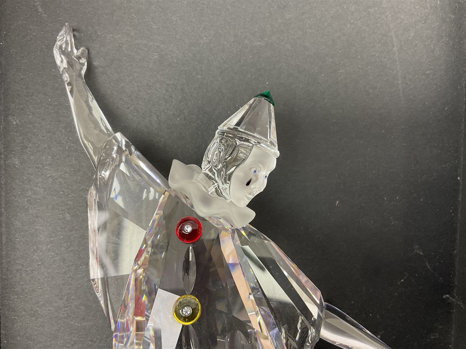 Swarovski Crystal Masquerade trilogy; 1999 Masquerade Pierrot, 2000 Columbine, 2001 Harlequin all with accompanying plaque, stand and original box, together with a glass display case with mirrored back and sides 