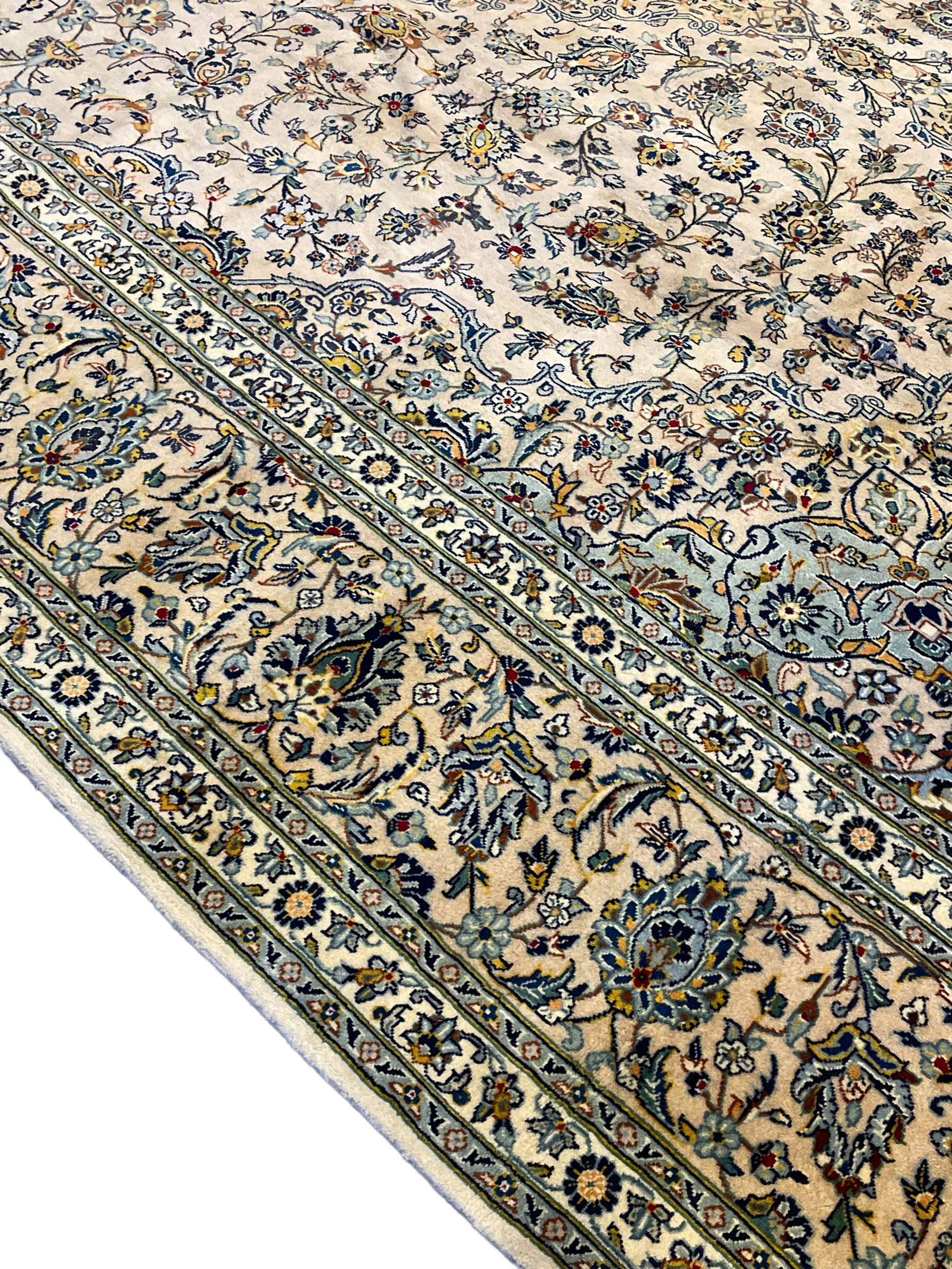 Central Persian Kashan pale khaki ground carpet, shaped central medallion enclosing small stylised motifs, the field decorated profusely with trailing foliate branches and plant motifs, guarded border with repeating floral design 