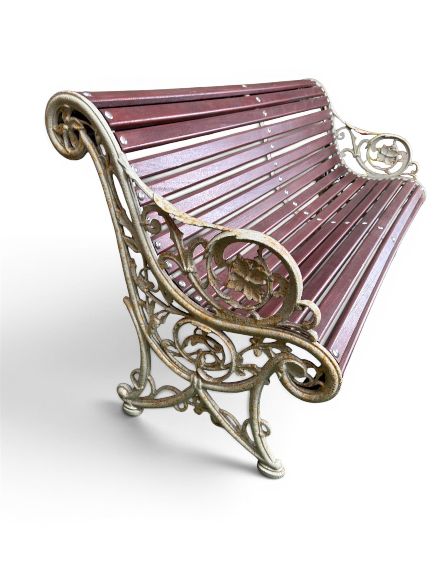 Large late Victorian cast iron garden bench, serpentine form with scroll back and seat, slatted with mahogany stained Sapele