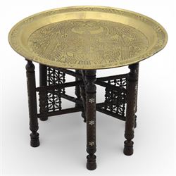 20th century Eastern brass charger topped table, the circular brass trap chased with an elephant, palm tress and flowering vines, supported upon a folding stand with six turned legs with inlaid detail, united by turned supports