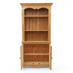 Contemporary pine kitchen dresser, moulded cornice over open plate rack with shaped frieze and two fixed shelves, enclosed lower section with panelled twin doors and shaped plinth base