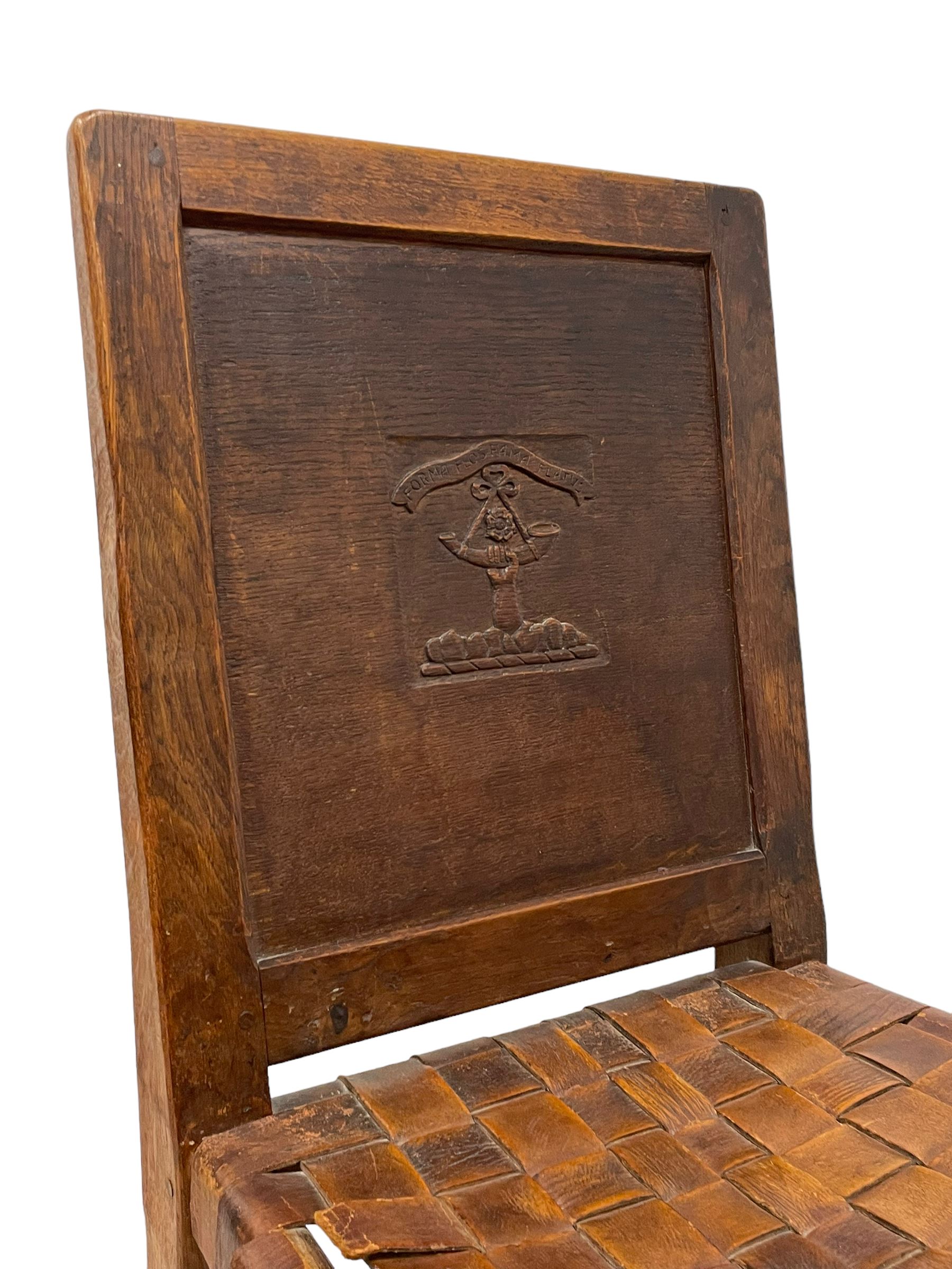Mouseman - circa. 1930s set of six (4+2) oak dining chairs, panelled back carved with the Bagshawe family crest, the moto 'Forma Flos Fama Flatus' over an arm grasping a bugle-horn with ribbon tie and Yorkshire rose motif, adzed frame, leather lattice strap seat, on octagonal supports united by stretchers, two carvers and four side chairs, each carved with mouse signature, by Robert Thompson of Kilburn 

Provenance: Owned since manufacture by the Bagshawe family, descendants of the Staithes Group Artist Joseph Richard Bagshawe RBA (1870-1909).