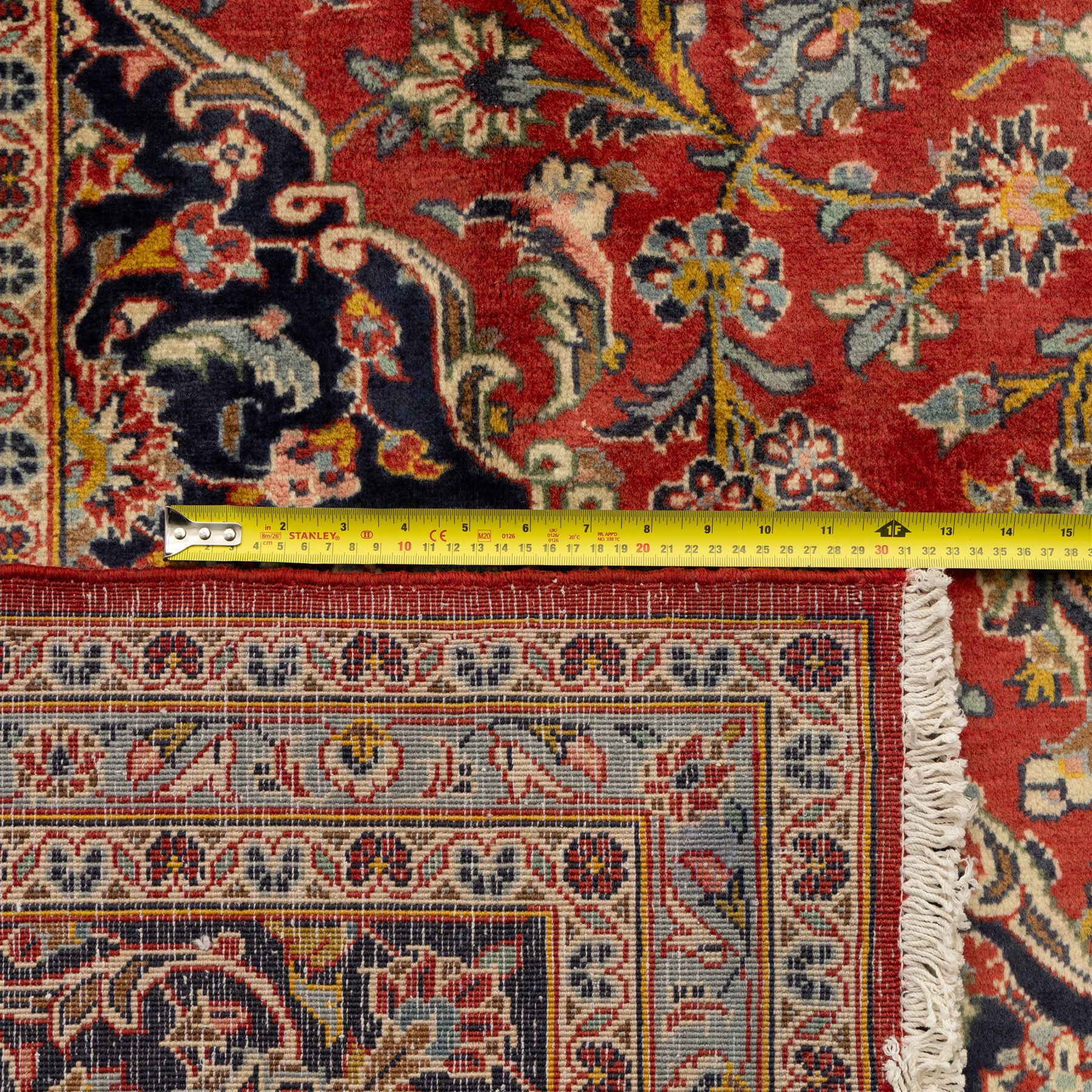 Persian Kashan carpet, the field in rich rust tone centred by an ivory and blue medallion with palmette extensions, surrounded by intricate foliate arabesques and stylised blooms, within triple floral borders incorporating palmettes and interlaced tendrils, woven in the region of Kashan