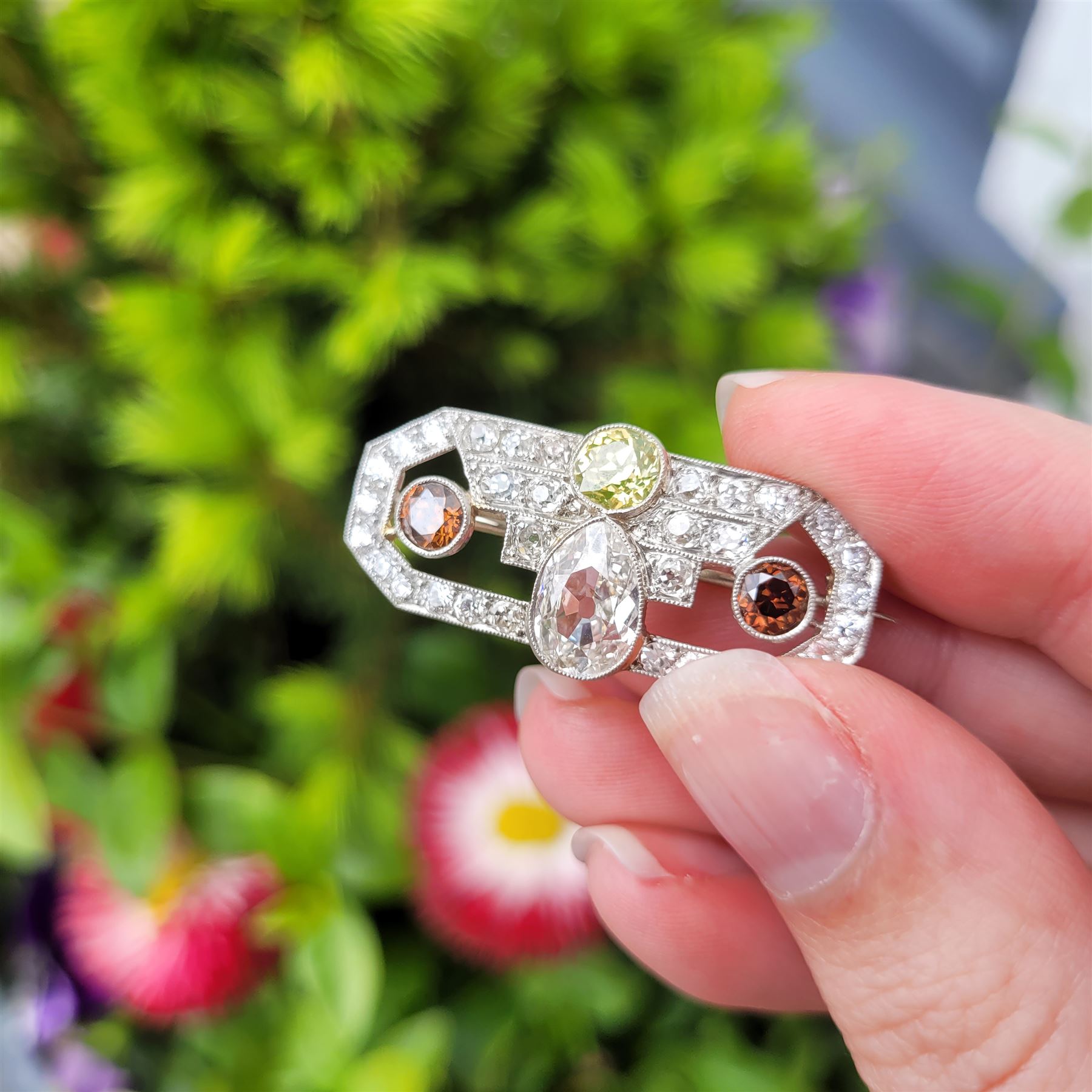 Early 20th century platinum diamond brooch, milgrain set with a pear cut faint brown diamond of approx 1.50 carat, an old cut fancy yellow / green diamond of approx 0.70 carat, and two old cut fancy orange / brown diamonds of approx 0.40 carat and 0.35 carat, surrounded by old cut white diamonds in an openwork setting, total white diamond weight approx 1.45 carat