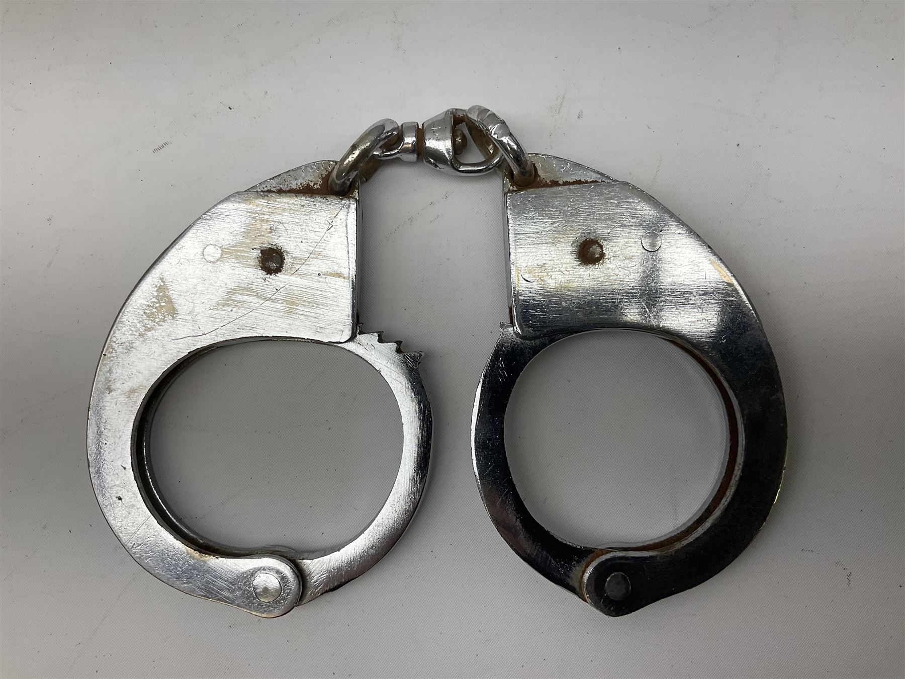 British Transport Police Custodian helmet with Queen's Crown plate; Hiatt & Co ebonised hardwood patrol truncheon; and pair of Hiatts 1960 hand-cuffs (3)