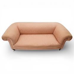 Victorian two seat sofa, upholstered in pink fabric, bowed form with scroll back and arms, raised on turned legs with castors