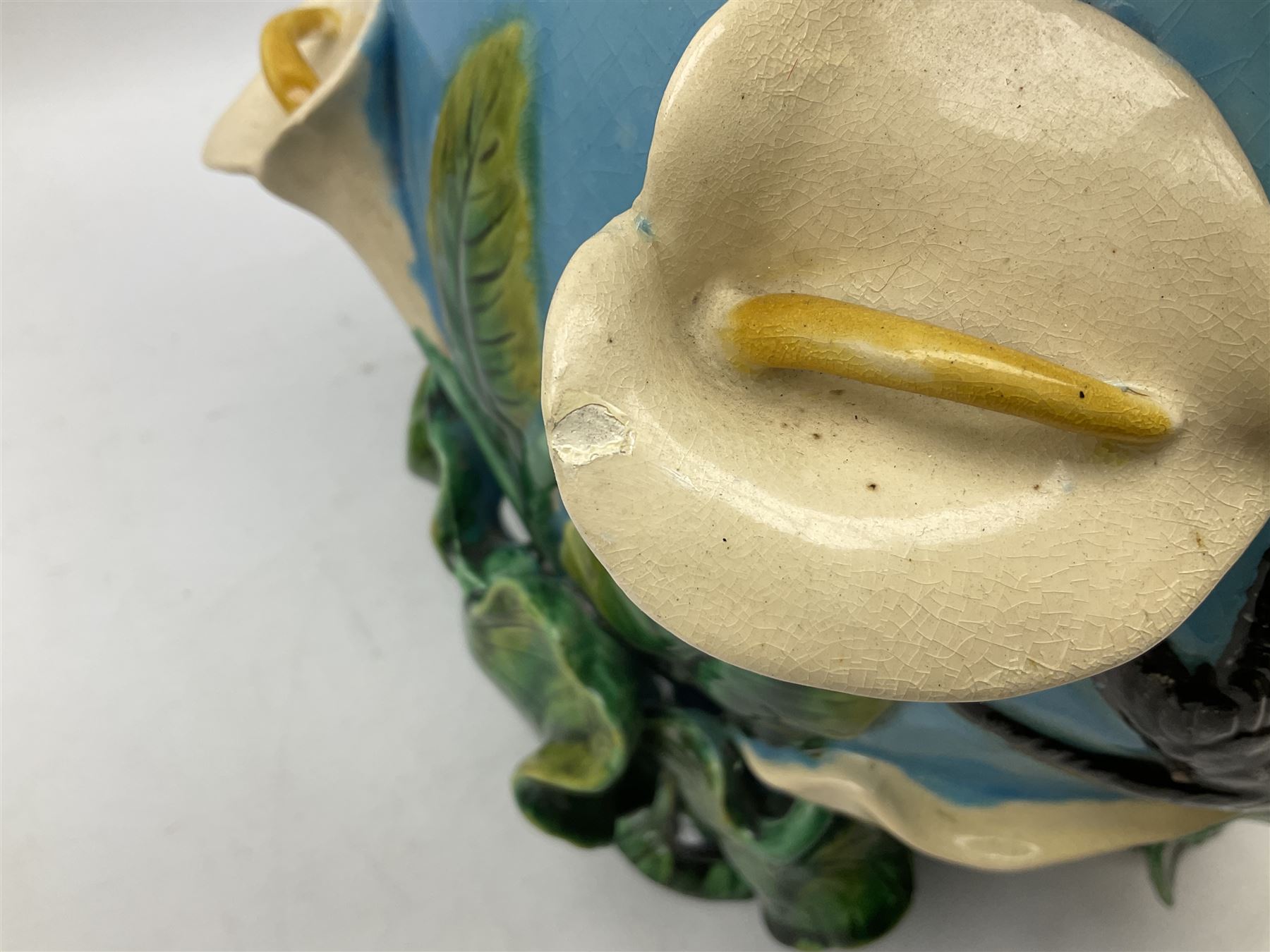 George Jones style majolica jardiniere of globular form, supported on four feet formed from modelled lily leaves growing up the side of the pot, with swallows flying amongst the white lily flowers, all set against a blue ground, with a pink interior, H27cm