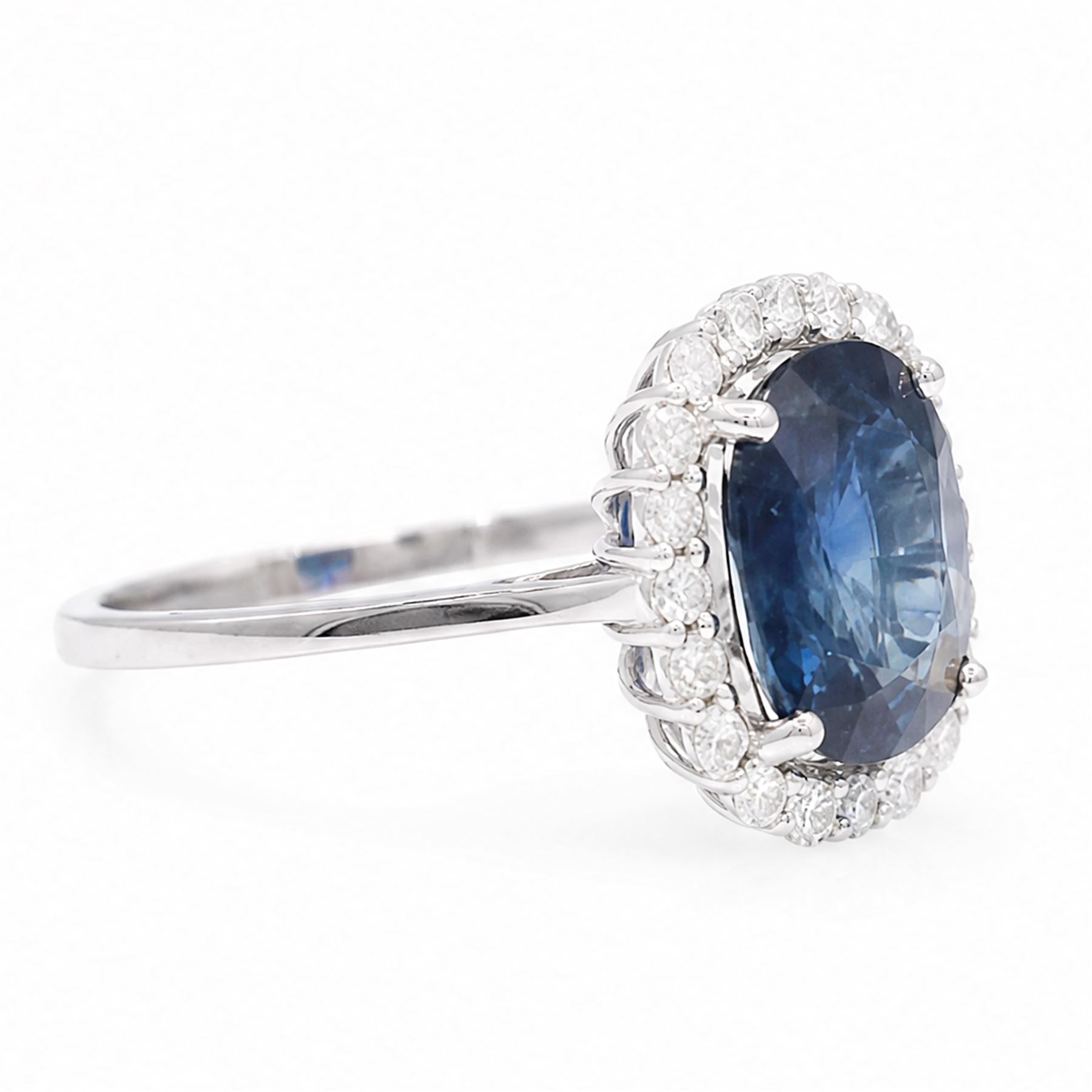 18ct white gold sapphire and diamond cluster ring, single cushion cut sapphire of approx 4.20 carat, surrounded by twenty round brilliant cut diamonds, stamped 750, total diamond weight approx 0.50 carat