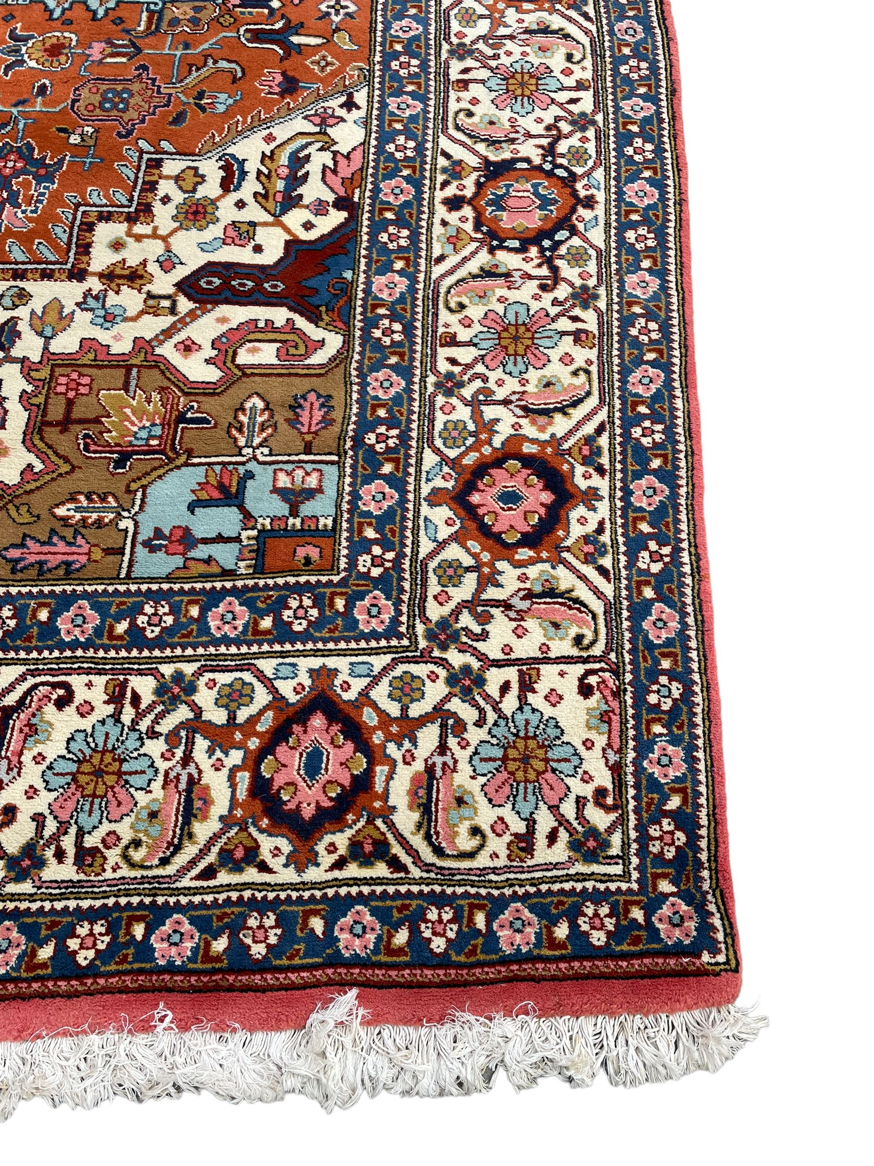 Large Persian carpet, the geometric and stylised floral medallion on rust ground field decorated with stylised plant motifs, guarded ivory border with repeating pattern