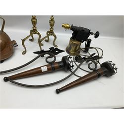 Two wood and metal candle wall sconces with fleur-de-lis mount, pair of brass fire dogs, brass paraffin blow torch converted to electric lamp, and brass kettle