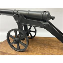 Black painted heavy cast metal model of a cannon on field carriage L41.5cm; loose mounted on oak base